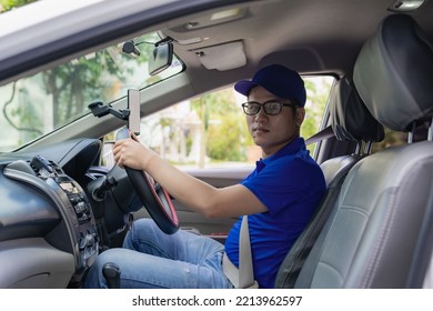 Asian Male Driver In A Blue Shirt, Hat, Glasses, Driving A Car