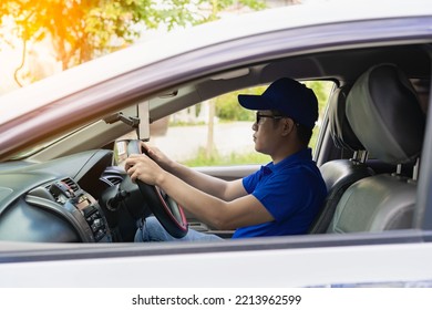 Asian Male Driver In A Blue Shirt, Hat, Glasses, Driving A Car