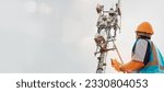 Asian male engineer safety helmet works in the field  high rise building inspecting telecommunication tower structures setting up electronic power grids and maintaining 5G networks for safety reasons.