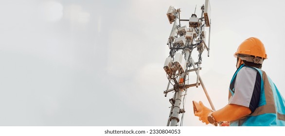 Asian male engineer safety helmet works in the field  high rise building inspecting telecommunication tower structures setting up electronic power grids and maintaining 5G networks for safety reasons.