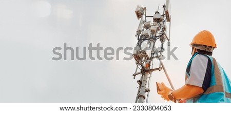 Asian male engineer safety helmet works in the field  high rise building inspecting telecommunication tower structures setting up electronic power grids and maintaining 5G networks for safety reasons.