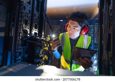 Asian male engineer using smartphone flash while inspecting the server in computer server room. database server management and maintenance concept - Powered by Shutterstock