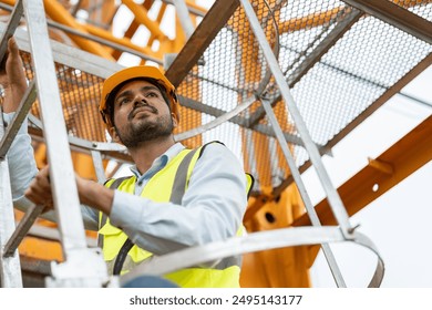 Asian male engineer wearing safety vests and helmet climbing metal ladder inspection and maintenance tower crane at construction site. - Powered by Shutterstock