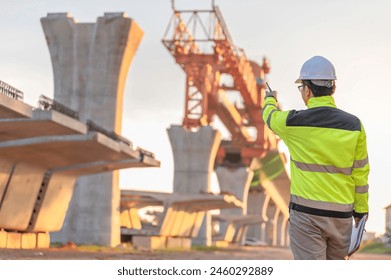 An Asian male engineer works at a motorway bridge construction site,Civil worker inspecting work on crossing construction,Supervisor working at high-speed railway construction site - Powered by Shutterstock