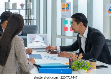 Asian Male Executive Explaining New Project To His Subordinates In His Office.