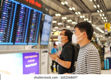 Asian Male With Face Mask Protection Againts Coronavirus Or Covid-19 , Covid19 And Omicron  Look At Flight Schedule Board At The Airport , Corona Virus And Health Protection Concept