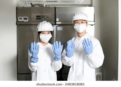 Asian male and female cooks working in a food factory - Powered by Shutterstock