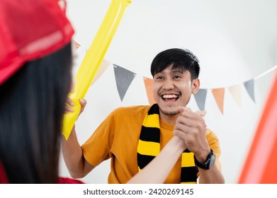 Asian male and female friends Watch the World Cup live broadcast on TV. Sports fans shout and hi five together, celebrating the sports team's victory. and eat snacks together at home - Powered by Shutterstock