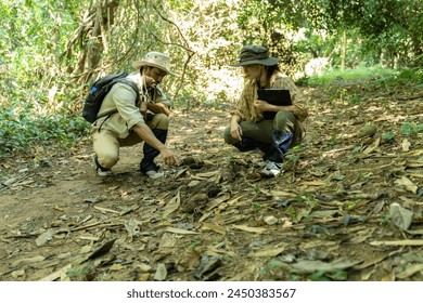 Asian male and female geologist researcher analyzing rocks with a magnifying glass in Mae Wang Nature Park - Powered by Shutterstock