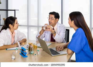 Asian Male And Female Medical Doctor Team Sitting At Desk And Meeting Discussion About Vaccine With Laptop Computer