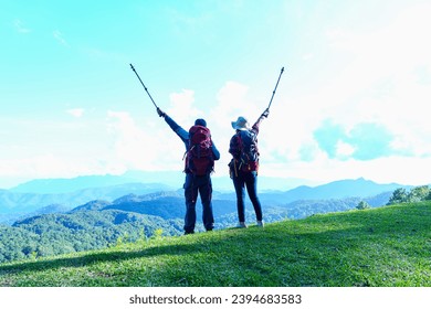 Asian Male and female standing raised hands with trekking poles on Lawn or green grass ground of camping ground, Asia couple hiking in mueang haeng camping ground, chiang mai, Thailand. - Powered by Shutterstock