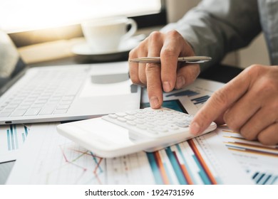 Asian male finance staff is calculating by using a calculator. Investment results to report to his boss at the meeting. On the table in the office, the concept of calculating investment results