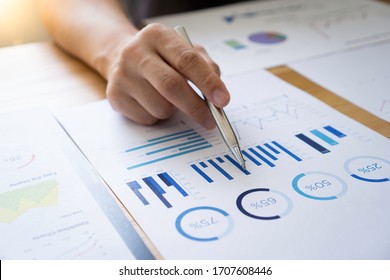 Asian male finance staff Is explaining the performance from the company's rapidly growing bar graph this year. To his boss On the desk at the office, Finance concept - Shutterstock ID 1707608446