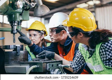 Asian male foreman manager showing case study of factory machine to two engineer trainee young woman in protective uniform. teamwork people training and working in industrial manufacturing business