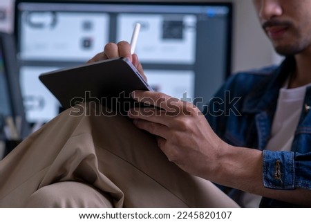 Asian male graphic designer working on tablet computer drawing sketches logo design. The concept of a new brand. Professional creative occupation with idea.