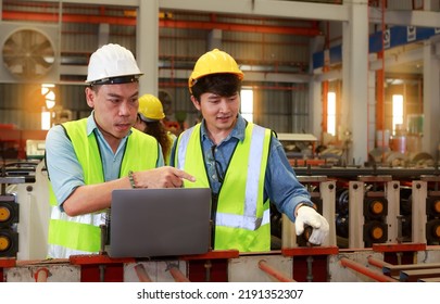 Asian Male Hard Hat Chief Engineer Uses Laptop To Train Workers To Check Checks Heavy Metal Machinery There Is A Team Working Behind The Scenes. Concepts, Factory Workers. Mechanical Engineering