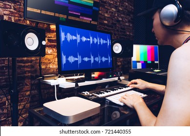 asian male hipster sound engineer working on computer in digital audio & video editing post production studio