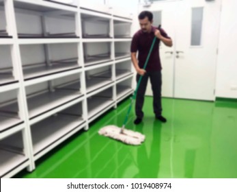 Asian Male Janitor Mopping Floor In Classroom Of School Blur Image Use For Background. Commercial Cleaning And Janitorial Services Concept.