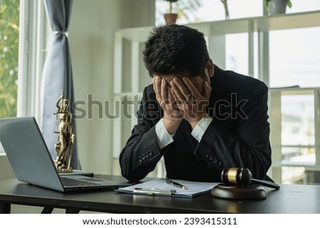 Asian male lawyer working in law office with hammer and scale and laptop, contract concept legal proceedings