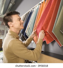 Asian Male Looking At Fabric Swatches In Retail Store.