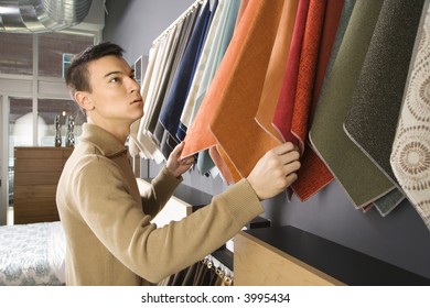 Asian Male Looking At Fabric Swatches In Retail Store.