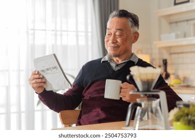 Asian male man gray hair senior retired enjoying coffee breakfast at kitchen counter weekend while reading newspaper Smiling senior man with book while sitting in kitchen at home healthy lifestyle - Powered by Shutterstock