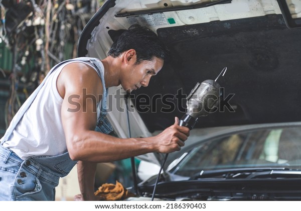 Asian male mechanic,\
engine mechanic with engine light, check engine failure, find the\
cause of broken car parts, provide professional car repair service\
in the garage.