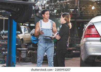 Asian Male Mechanic Talks To Female Customer To Check Car Engine And Change Oil In Garage