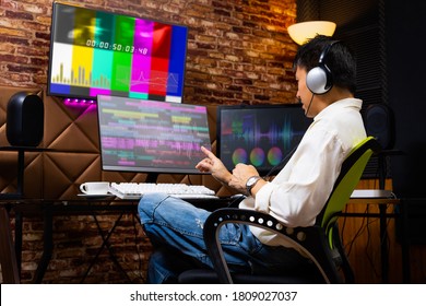asian male media content creator editing video footage on computer in home studio. post production, broadcasting concept