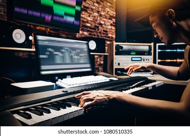 asian male music arranger hands composing song on midi piano & professional audio equipment in digital recording studio