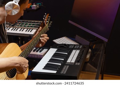 asian male musician, composer, artist enjoy playing acoustic guitar for recording on computer in home studio. music production or music e-learning on internet concept