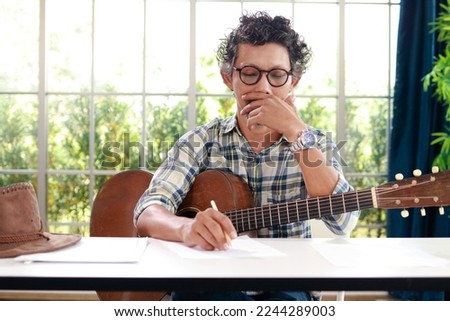 Asian male musicians sitting guitar instrument Acoustic and currently composing music. music concept
