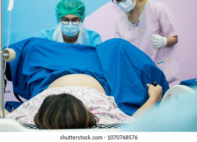 Asian Male Obstetrician And Scrubs Nurse Are Delivered To The Pregnant Woman In The Delivery Room Of The Hospital,A Team Of Doctors And Nurses Ready To Deliver In Labor Room,Health Care Professionals,