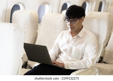 Asian Male Passenger In Airplane Use Computer Notebook Laptop And Wifi On Board, Young Asian Business Man Use Computer Laptop Traveling By Airplane Connecting Wifi.