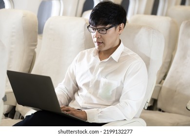 Asian Male Passenger In Airplane Use Computer Notebook Laptop And Wifi On Board, Young Asian Business Man Use Computer Laptop Traveling By Airplane Connecting Wifi.