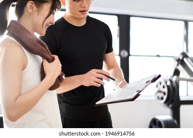 Asian male personal trainer giving training advice - Shutterstock ID 1946914756