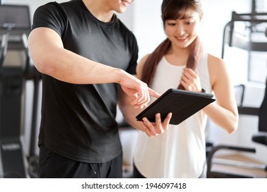 Asian Male Personal Trainer Teaching Using A Tablet