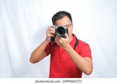 An Asian male photographer wearing red shirt taking a picture with white background. Travel concept - Powered by Shutterstock