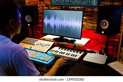 Asian Male Producer Recording, Editing, Mixing Sound On Computer In Home Studio, Music Production Concept