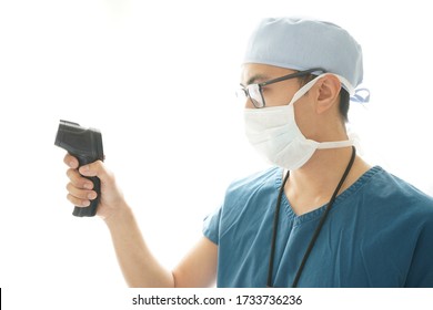 Asian Male Registered Nurse With A Surgical Mask Holding A Thermo Gun To Detect Fever During Covid-19 Pandemic. 