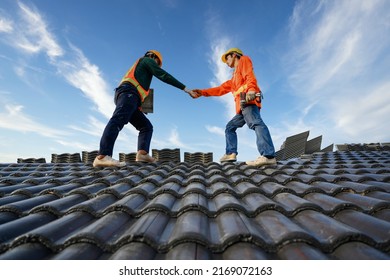 Asian Male Roof Repairman Work Together As A Team Standing On The Roof Ceramic Or Cement Roof Tiles On The Construction Site