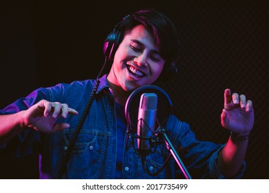 Asian Male Singer Recording Songs By Using A Studio Microphone And Pop Shield On Mic With Passion In A Music Recording Studio. Performance And Show In The Music Business.