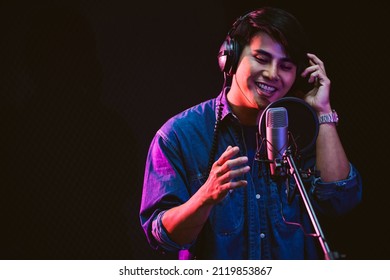 Asian Male Singer Recording Songs By Using A Studio Microphone And Pop Shield On Mic With Passion In A Music Recording Studio. Performance And Show In The Music Business. Focus On Male Face