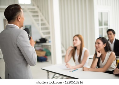 Asian male speaker is speaking at seminars and workshops to the people in the meeting. Participants are raising their hands to ask questions. - Powered by Shutterstock