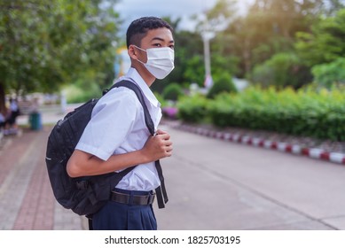 An Asian Male Student In White High School Uniforms Wearing The Mask Stand On The Side Of The Road Waiting For Car To Go Back Home After School During The Coronavirus 2019 (Covid-19) Epidemic.