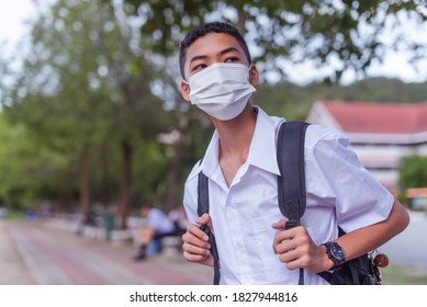 An Asian Male Student In White High School Uniforms Wearing The Mask Stand On The Side Of The Road Waiting For Car To Go Back Home After School During The Coronavirus 2019 (Covid-19) Epidemic.