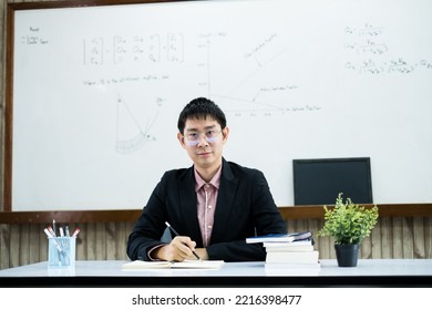 An Asian Male Teacher At The University Is Preparing Lessons To Teach In The Classroom.