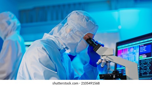 Asian Male Technician In Sterile Coverall Work At Semiconductor Manufacturing Plant By Microsope