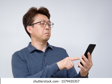 Asian Male Trying To Read Something On His Mobile Phone. Poor Sight, Presbyopia, Myopia.