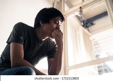 Asian Male Unemployed Worker Sitting On Chair Feeling Stress And Unhappy That Have No Job Due To Covid-19 Virus Cause Him To Be Laid Off. Man Thinking How To Find Money In Bad Global Economic Crisis.